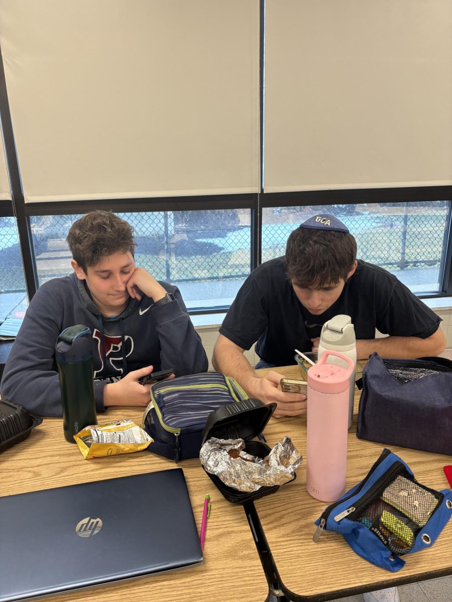 Juniors Noah Stoch and Max Lefkowitz check their phones while enjoying a snack after school.