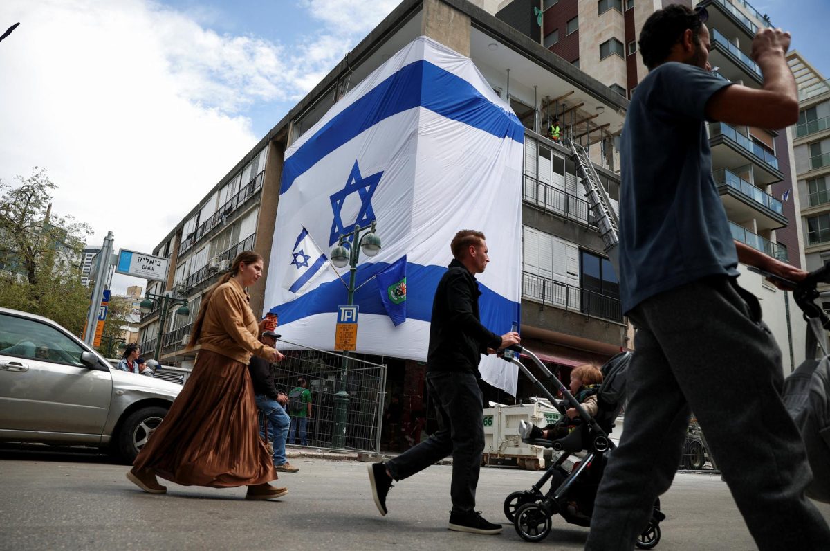 People pass by an impact site, which is wrapped in a large Israeli flag, in the aftermath of missile attacks launched from Iran into Israel on Monday, amid the U.S.-Israel conflict with Iran, in central Israel, April 7, 2026. REUTERS/Florion Goga